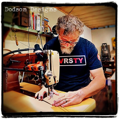 Donald Dodson in his leather workshop, stitching together items with his industrial leather sewing machine.