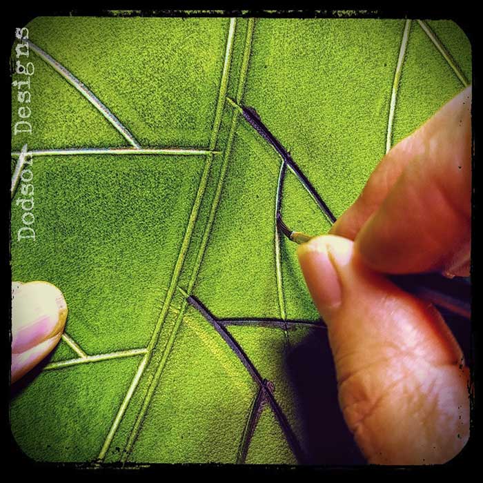 Hand painting the veins in a green dyed piece of leather.