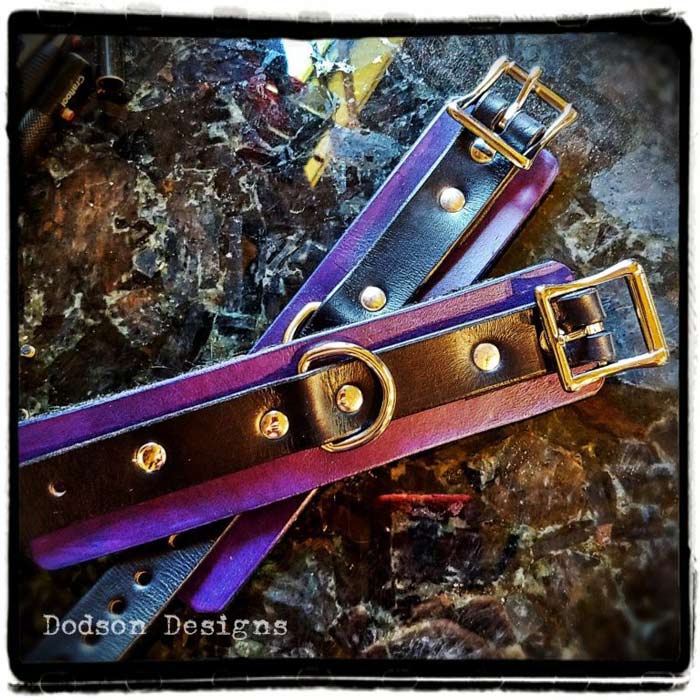 Two leather cuffs in purple and black with a buckle closure.