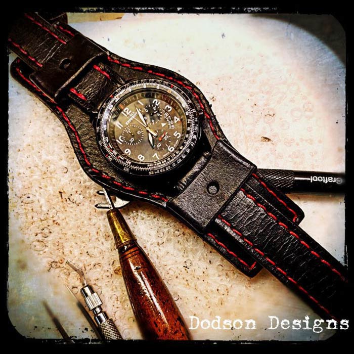 Black leather watch band with red stitching.